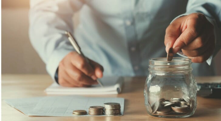 Man putting coins in a jar